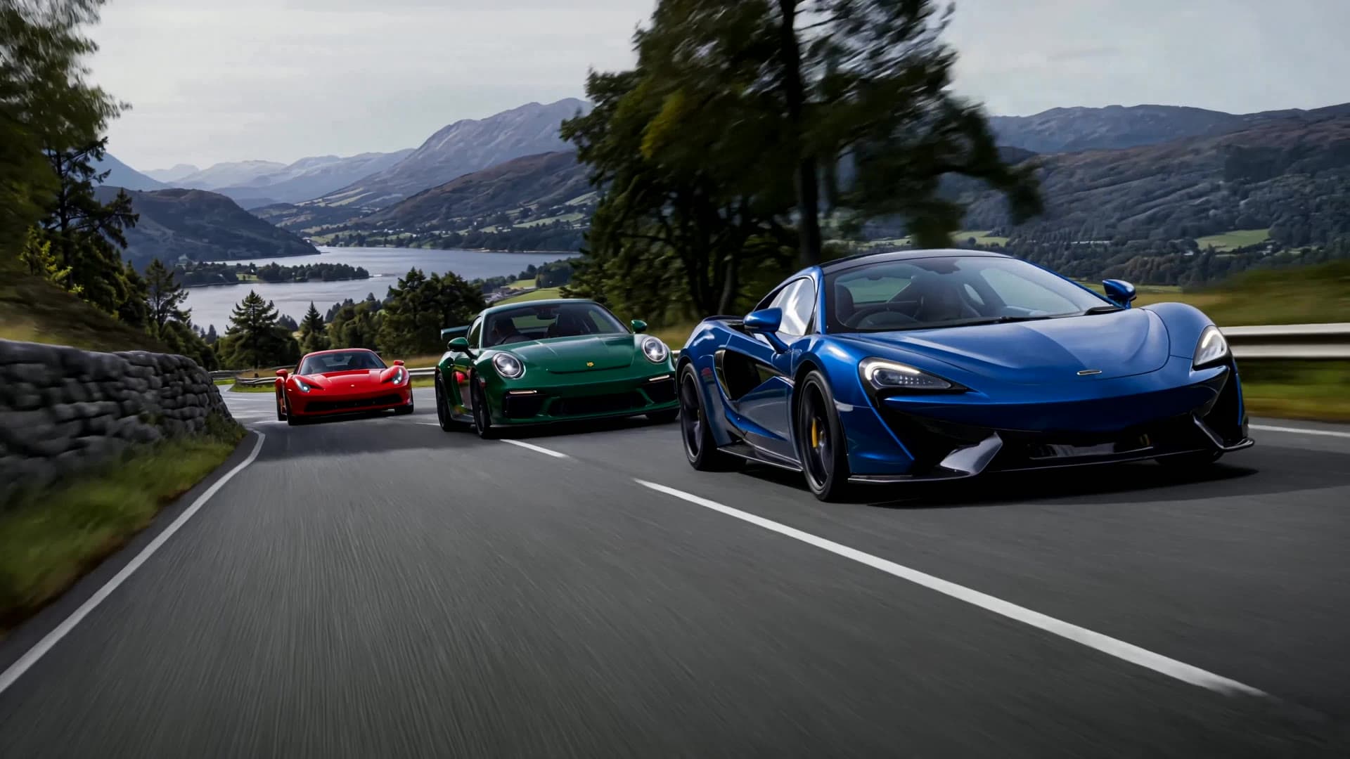 Three supercars in convoy, a blue McLaren, a green Porsche 911 GT3 and a red Ferrari, on a winding Lake District road under a stormy sky, a lake in the valley behind